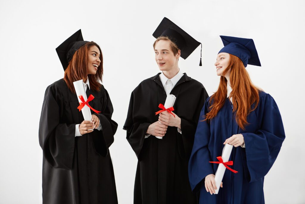 Three graduate students smiling while looking at their degree, representing our study abroad services.